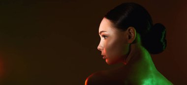 Renkli ışıklar içinde güzel bir genç kadın. Makyajlı ve parlak vücutlu güzel kız.