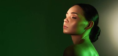 Renkli ışıklar içinde güzel bir genç kadın. Makyajlı ve parlak vücutlu güzel kız.