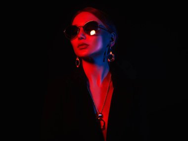 Renkli ışıklar içinde güzel bir kadın. Sanat tasarımı, güneş gözlüğü ve mücevher takan renkli kız.