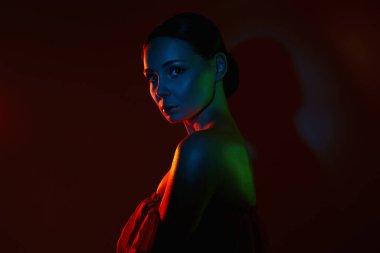 Renkli parlak ışıklar içinde güzel bir kadın. Siyah stüdyodaki kızın renkli silueti