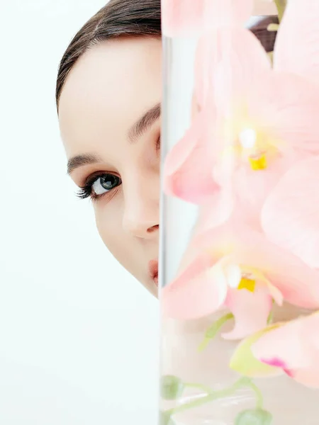 美丽的年轻女子和花朵在瓶中 具有兰花的女孩的美丽画像 洁肤脸 — 图库照片