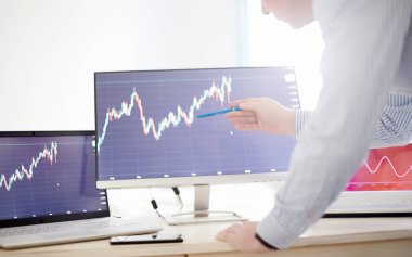 Yönetici ofiste çalışıyor, grafiklere bakıyor. Tüccar ya da Komisyoncu. Eğitim