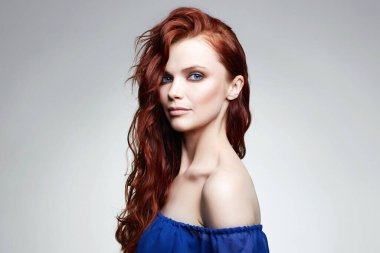 Kızıl kıvırcık saçlı ve makyajlı güzel bir kadın. Mavi elbiseli, şehvetli, kızıl saçlı kadın.