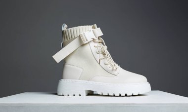 Tahta masada beyaz çizmeler. Moda ayakkabıları hala hayat. Stüdyoda şık bir fotoğraf.