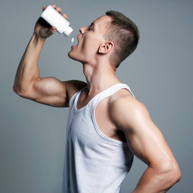 Vücut geliştirici haplar, steroidler. Şişeli yakışıklı fitness çocuğu. Vücut kaslı spor adamı. Spor beslenmesi