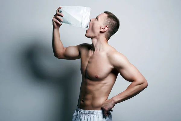 bodybuilder eating sports nutrition. Handsome Fitness Boy with bottle. Sport body muscular Man. Gym