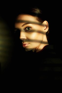 Güzel bir kızın yüzündeki ışık. Karanlıktaki şehvetli genç kadın