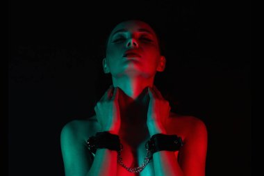 Kelepçeli güzel kız. Renkli ışıklar içinde güzel bir genç kadın. Sanat tasarımı, parlak vücutlu renkli bir kız. ellerim bağlı