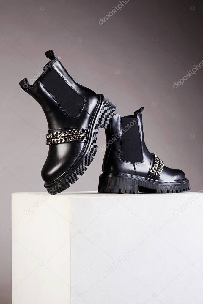 Fashionable black chelsea shoes with chain. fashion trendy boots still life