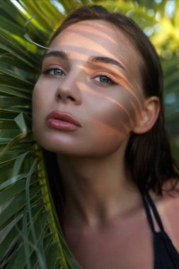 Gün batımında güzel bir yaz kızı. Palmiye yapraklı genç seksi kadın. Güzellik Portresi