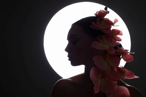 蘭の花を持つ美しい若い女性 女性のシルエットと花 — ストック写真