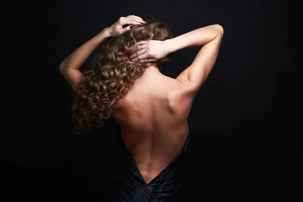 長い巻き毛を持つ美しい女性 黒のドレスでエレガントな女性 女性の背中 — ストック写真