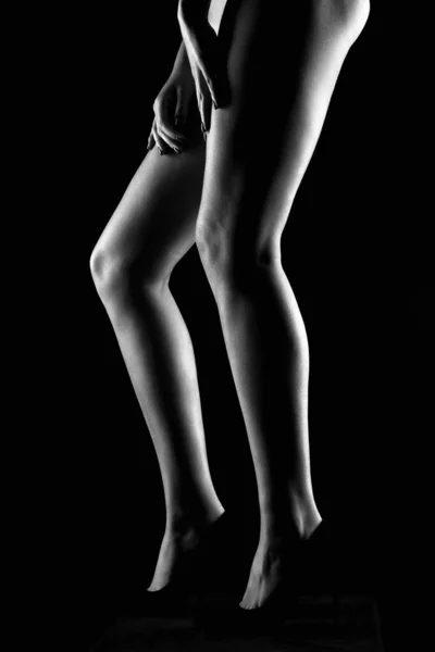 ハイヒールを履いた女性の足です 暗闇の中の女の子のシルエット 白黒写真です — ストック写真