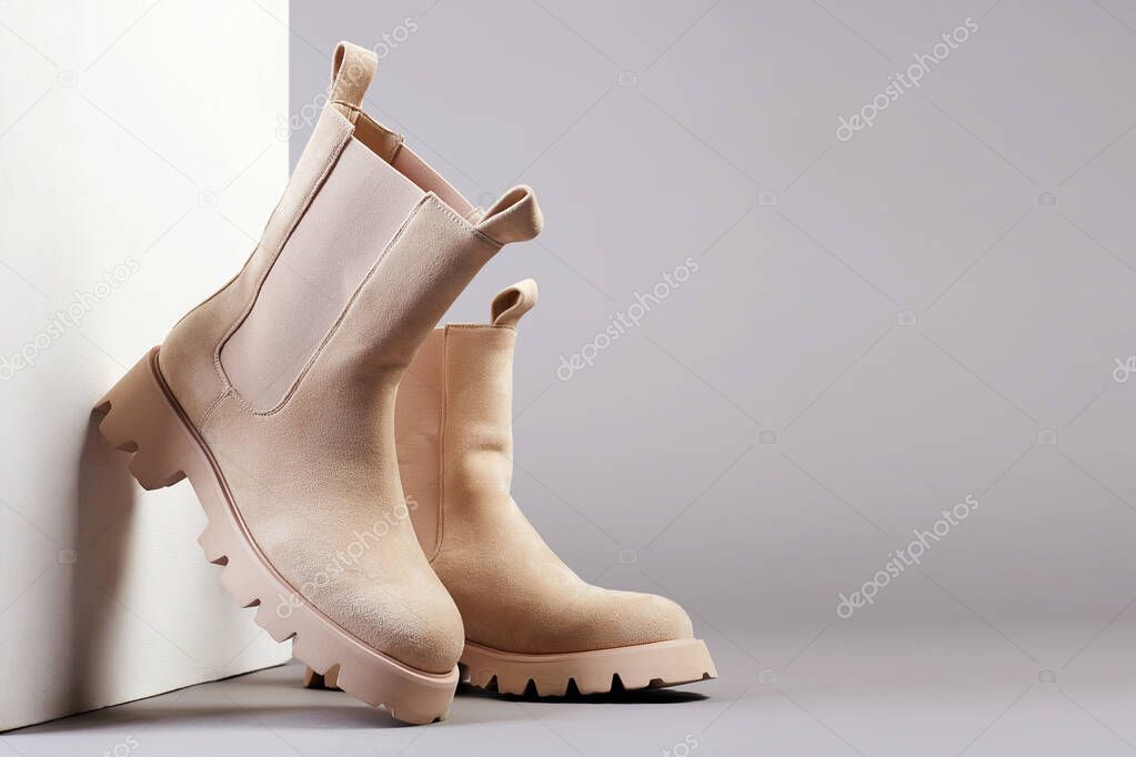 Trendy boots with wooden wall. fashion female shoes still life. stylish chelsea boots