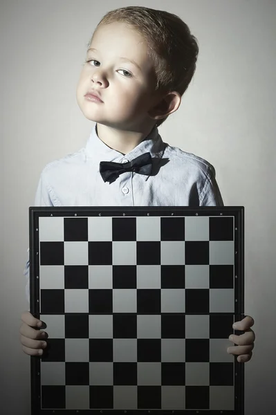 Menino com chessboard.fashion children.Bow-tie.Little gênio Criança. Jogo inteligente.Emoção — Fotografia de Stock
