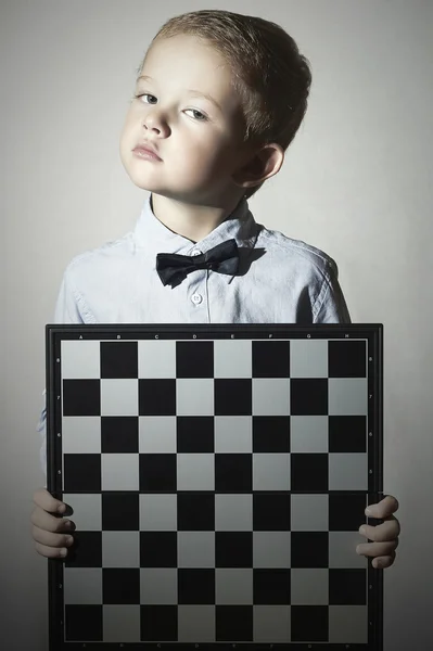 Ragazzino con scacchiera .fashion children.Bow-tie.Piccolo genio Bambino. Gioco intelligente.Emozione — Foto Stock