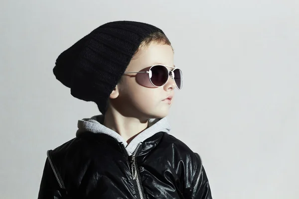 Fashionabla liten pojke i solglasögon. Child.Winter style.kids fashion.posing liten modell i svart mössa — Stockfoto