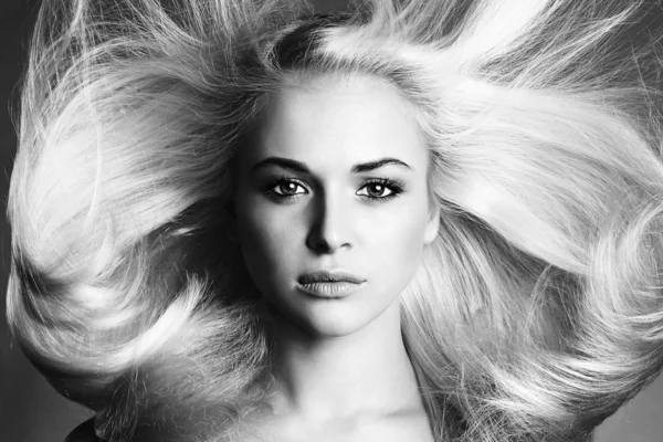 Монохромный портрет молодой женщины, блондинка, здоровая прическа, салон красоты, летающие волосы. — стоковое фото