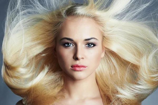 Krásná mladá žena s dlouhými vlasy na modrém pozadí. Blonďatá girl.hairstyle. Kosmetický salon — Stock fotografie