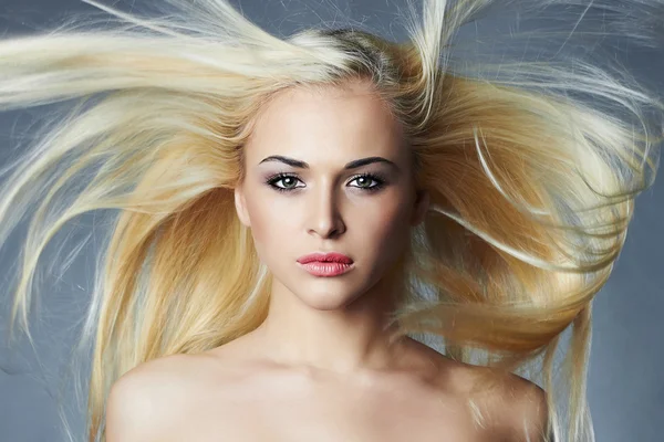 Piękna młoda kobieta z długimi włosami na niebieskim tle. Blond girl.hairstyle. Salon piękności — Zdjęcie stockowe