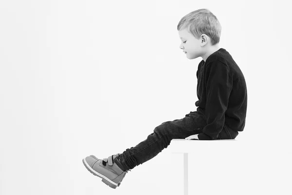 Monochrome portrait of Fashionable little boy sitting on a table — Stock Photo, Image