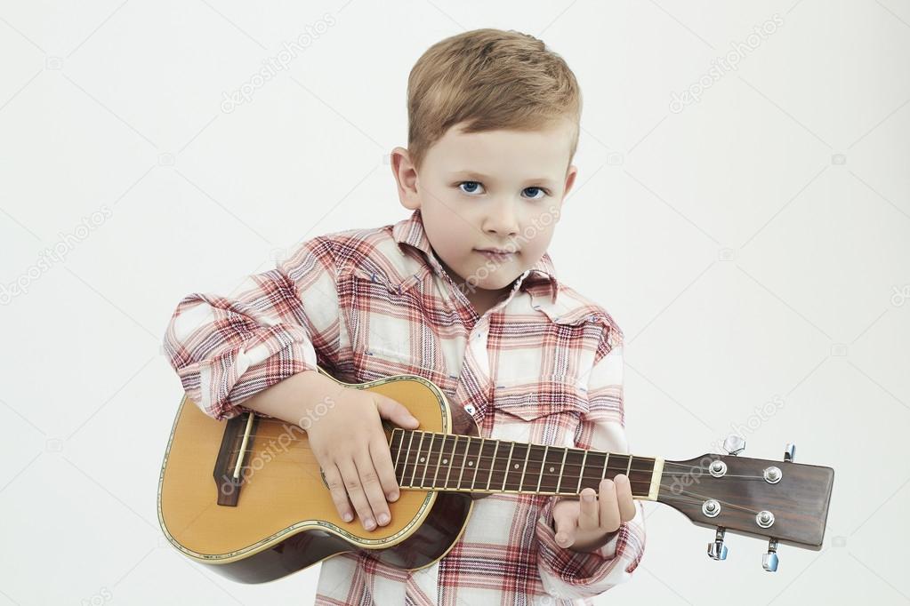 funny child boy with guitar. fashionable country boy playing music