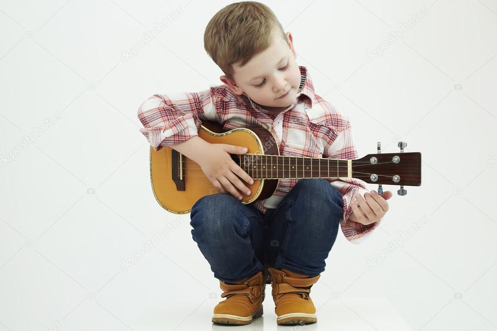 funny child boy with guitar. fashionable country boy playing music