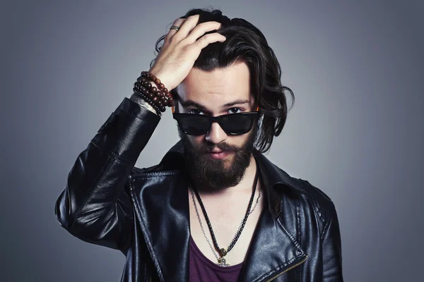 Fashionable handsome man in a leather jacket. Brutal bearded Sexy boy in trendy sunglasses.rock and roll — Stockfoto