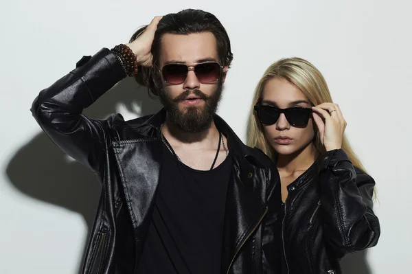 Hermosa pareja de moda hermosa en ropa negra con gafas de moda juntos. Hipster chico y chica. Joven barbudo y rubia en gafas de sol — Foto de Stock