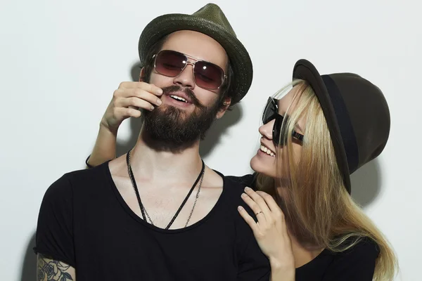 Belo casal feliz em chapéu vestindo óculos da moda juntos. Rapaz e rapariga hipster. Barbudo jovem e loira em óculos de sol — Fotografia de Stock