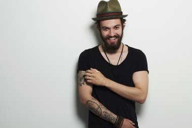 young bearded man. Smiling Hipster boy.handsome man in hat.Brutal bearded boy with tattoo