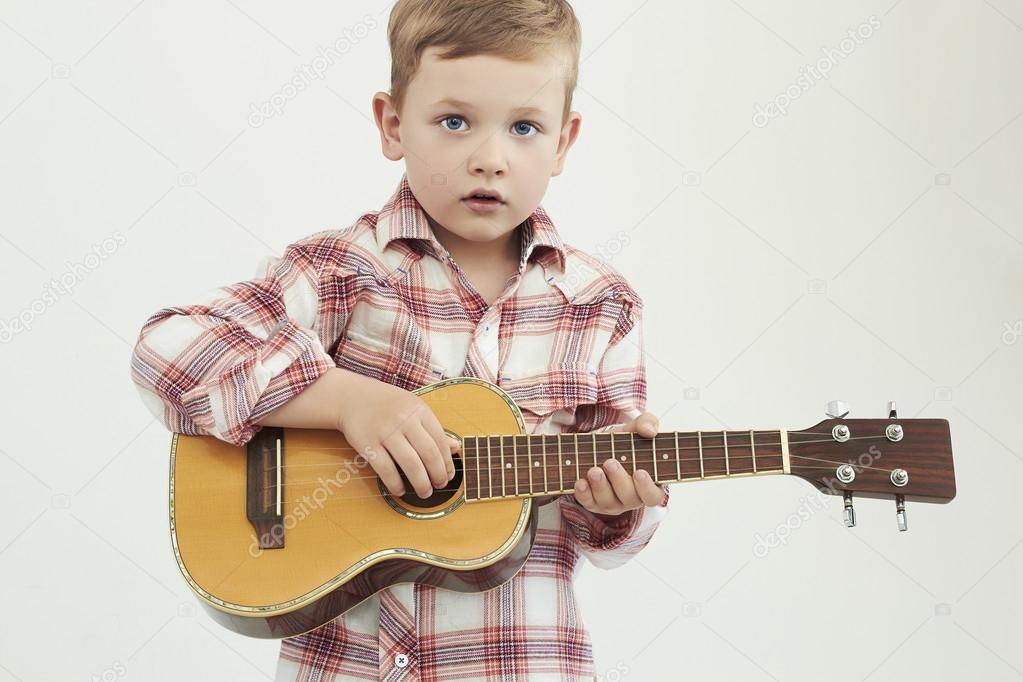 funny child boy with guitar. fashionable country boy playing music