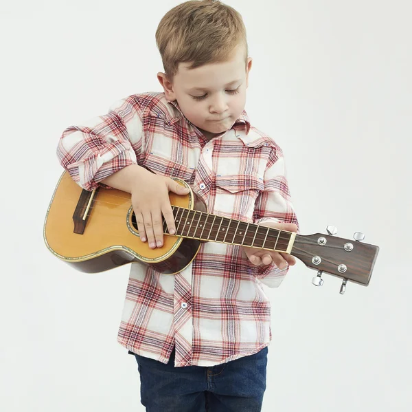 Смешной мальчик с гитарой. модный деревенский мальчик играет музыку — стоковое фото