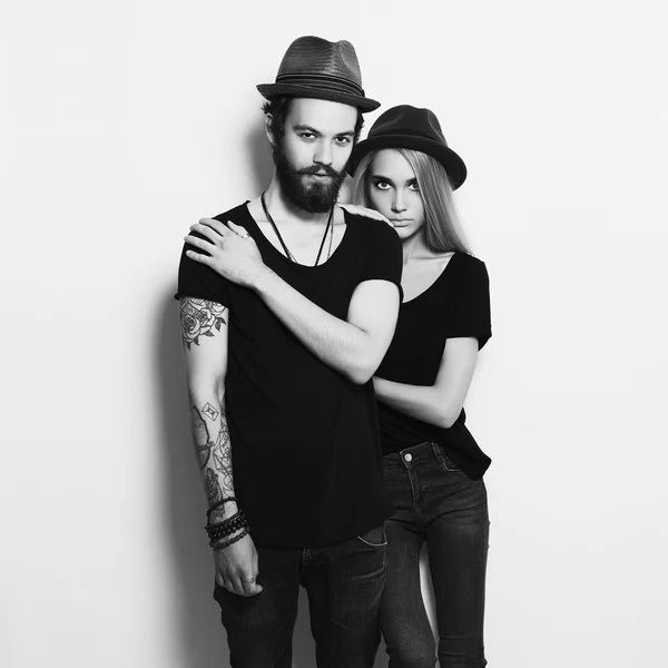 Fashion beautiful couple in hat together. Hipster boy and girl. Bearded young man and blonde. Tattoo — Zdjęcie stockowe