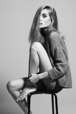 tek renkli bir taburede oturan güzel sarışın kadın portresi. Güzel kız