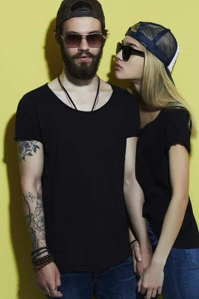 Moda hermosa pareja en sombrero juntos. Hipster chico y chica. Joven barbudo y rubia en gafas de sol. tatuaje —  Fotos de Stock