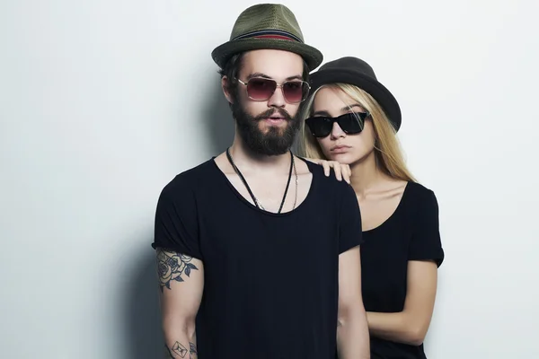 Hermosa pareja en sombrero juntos. Hipster chico y chica. Joven barbudo y rubia en gafas de sol —  Fotos de Stock