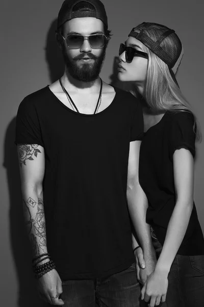 Moda hermosa pareja en sombrero juntos. Hipster chico y chica enamorados. Joven barbudo y rubia en gafas de sol. tatuaje —  Fotos de Stock