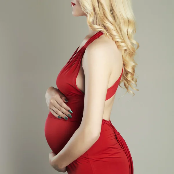 ผู้หญิงสาวที่มีความสุขตั้งครรภ์ ผู้หญิงผมบลอนด์ท้องสวยในชุดสีแดง — ภาพถ่ายสต็อก