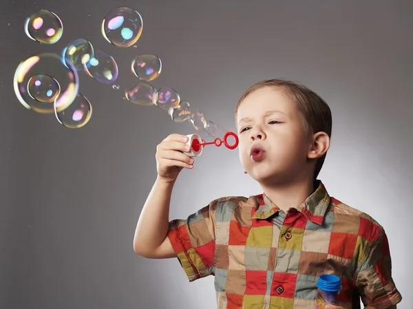 Divertido pequeño niño soplando jabón bubbles.happy niño — Foto de Stock