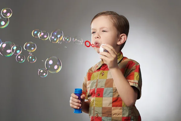 Lustige kleine Junge pustet Seifenblasen. — Stockfoto