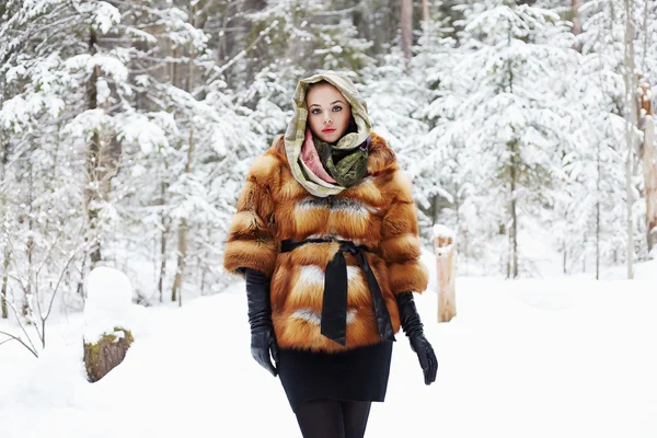 Modelo de belleza en bosque de invierno. hermosa mujer joven en abrigo de piel de moda, guantes de cuero y bufanda — Foto de Stock