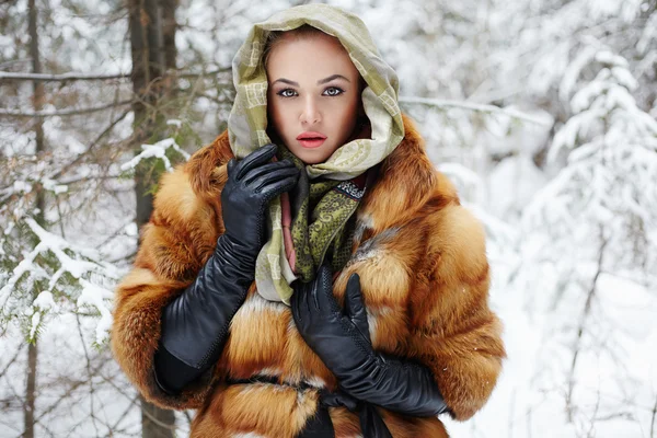 Modelo de belleza en bosque de invierno. hermosa mujer joven en abrigo de piel de moda, guantes de cuero y bufanda. siberiana — Foto de Stock