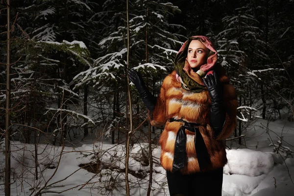 Schoonheid model meisje in nacht winter forest. mooie jonge vrouw in modieuze bontjas en scarf.blond girl.snow rond — Stockfoto