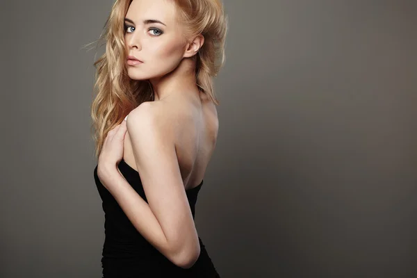 Schöne junge Frau mit blonden Haaren. Mädchen in schwarzem Kleid auf grauem Hintergrund — Stockfoto