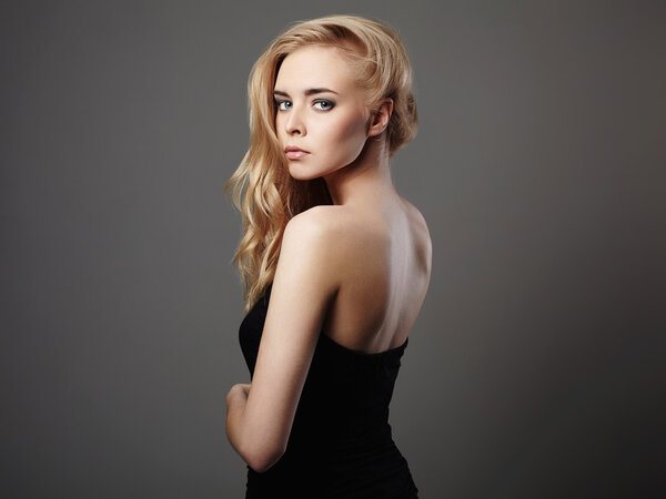 Fashion portrait of beautiful young woman with blond hair. Girl in black dress