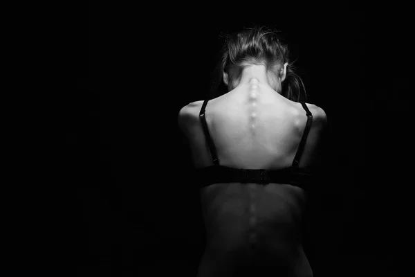 Грустная женщина с обнаженной спиной на черном фоне. — стоковое фото