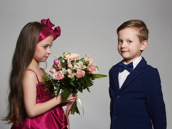 Pojke ger en flicka flowers.little vackra couple.kids kärlek, rosor bukett — Stockfoto