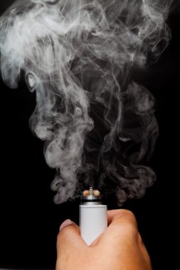 Elektronik sigara veya vaper aktive olduğunu ve insan eli, siyah renkli bir arka planla bir bulut yayın