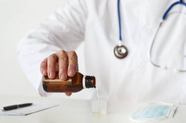 Doktor bir bardağı öksürük şurubuyla dolduruyor.. 